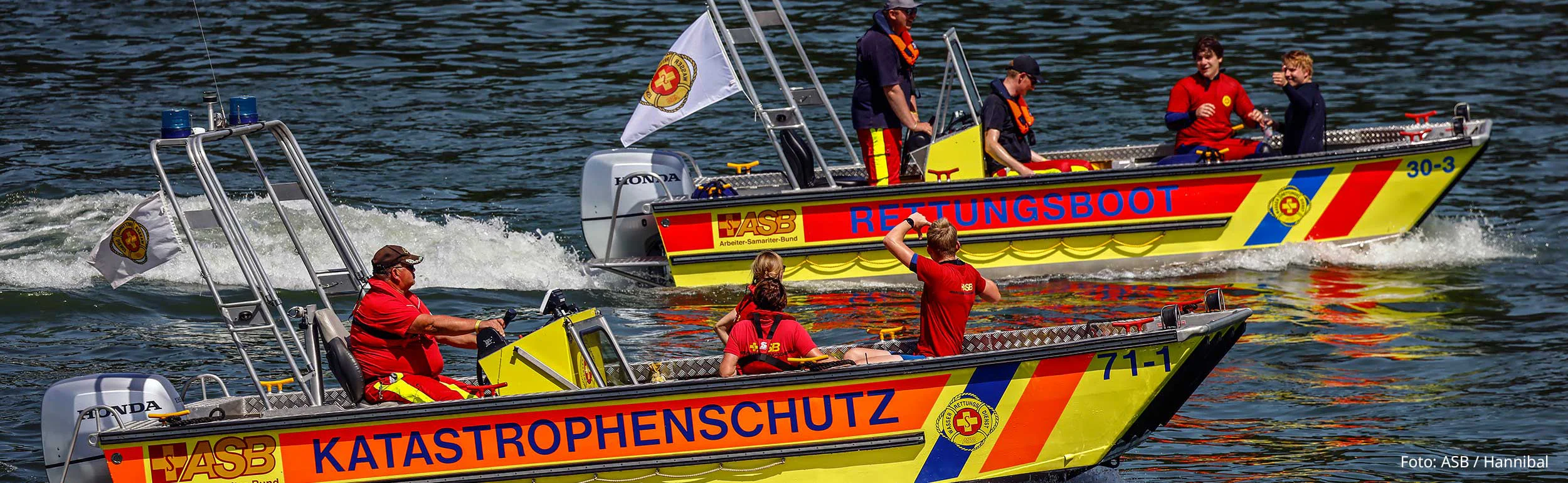 Wasserrettungszug und Rettungsboot fahren nebeneinander im Wasser.