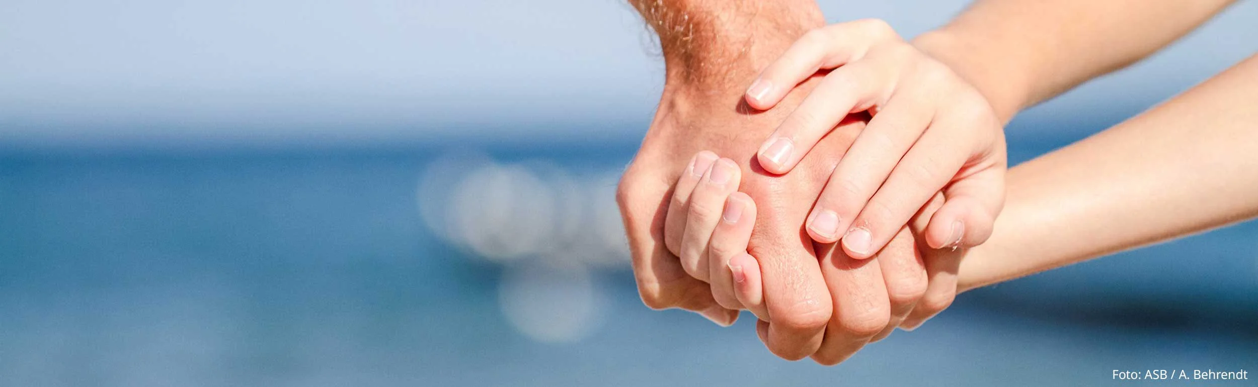 Erwachenen- und Kinderhand verbunden am Strand