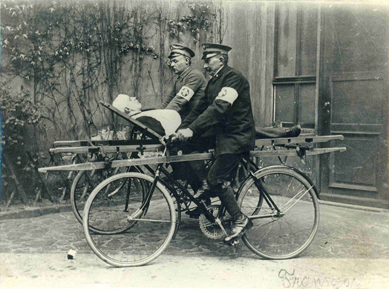 Historisches Foto aus den 1930er Jahren mit Holzfahrradtrage und zwei Samaritern auf Fährräder links und rechts