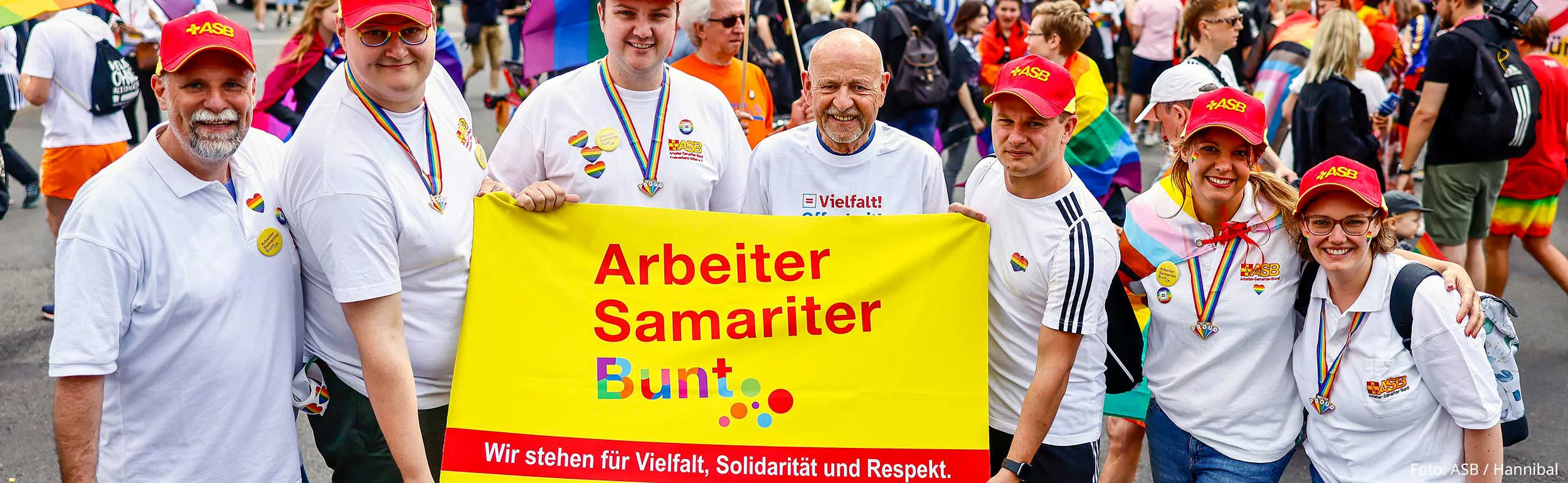 Sieben Samariter:innen halten buntes Transparent in die Kamera beim CSD 2023